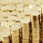 Прогноз выпуска драгоценных монет России: 2015 год На переднем плане - аккуратные стопки золотых монет, на заднем - рассыпанные золотые монеты