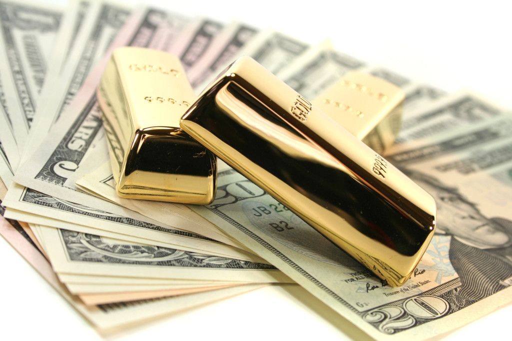 Золотые слитки поверх купюр долларов США