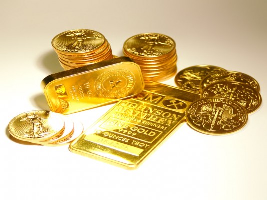 Золотой слиток и золотые монеты на белом фоне
